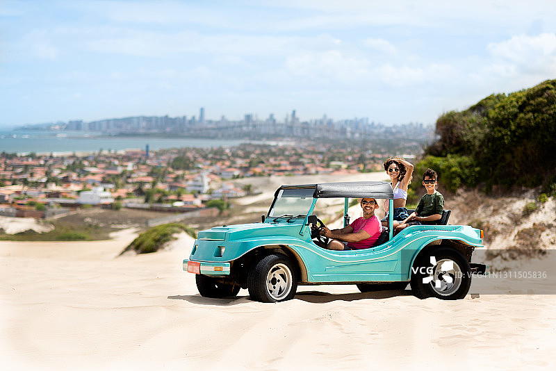 微笑的父亲开着沙滩车带着孩子们兜风图片素材