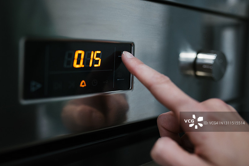 白人女性按下烤箱控制按钮的特写图片素材