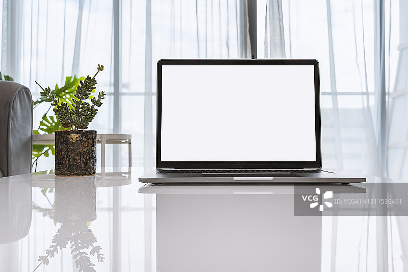 白色桌面上带有空白白色屏幕的笔记本电脑模型图片素材