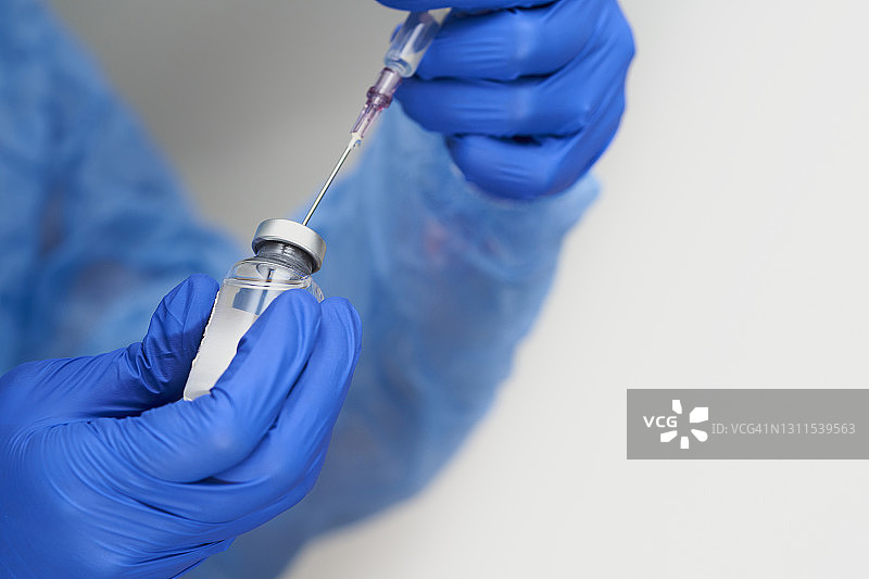 从玻璃瓶中抽取药物到注射器中，安瓿瓶和注射器特写图片素材