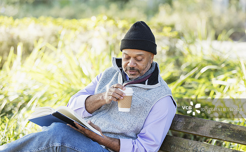 非裔美国男人在公园长椅上读书图片素材