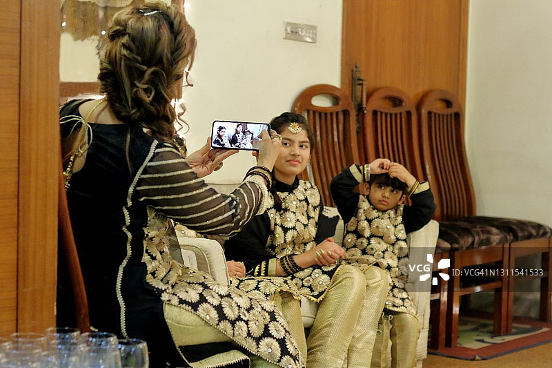 时髦的母亲用手机相机给女儿们拍照图片素材