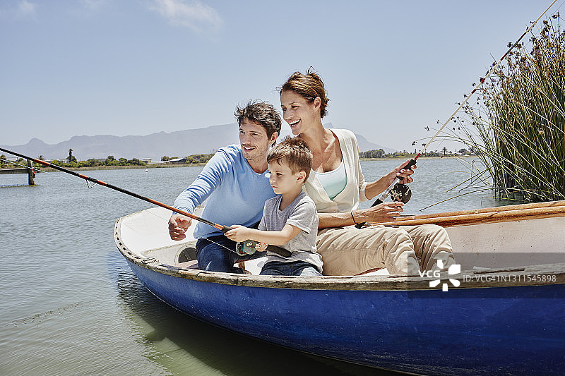 父母和儿子坐在湖上划艇钓鱼图片素材