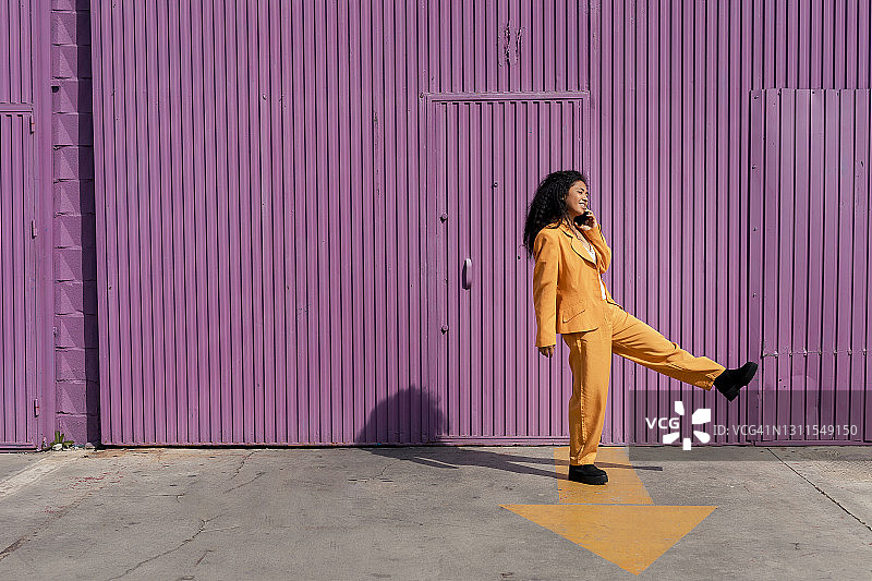 年轻女人在小屋旁的人行道上边跳舞边使用手机图片素材