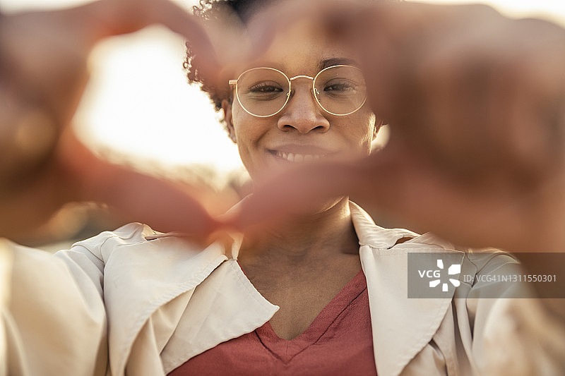 微笑的女人在户外用手势比心图片素材