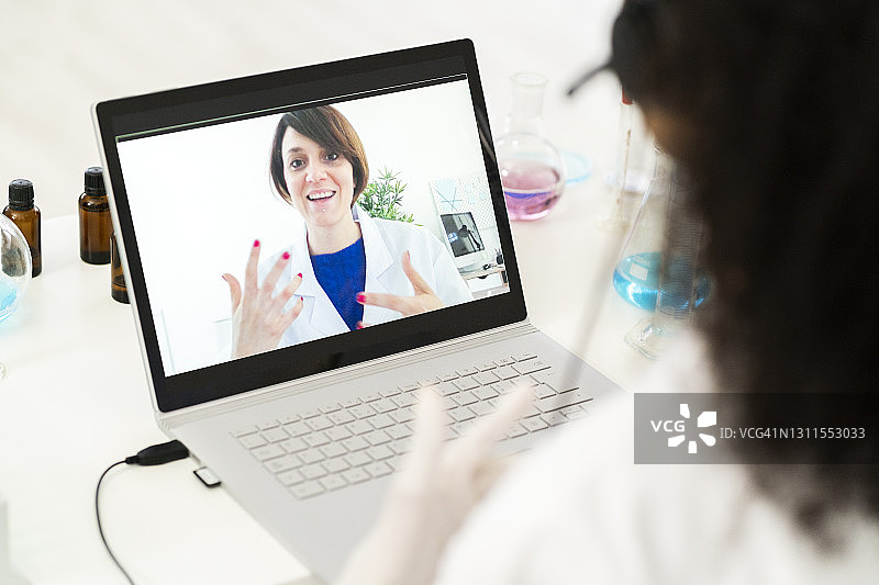女医生在实验室通过笔记本电脑进行视频通话讨论图片素材