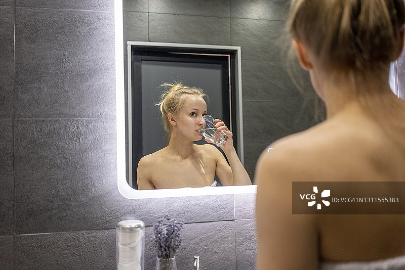 女人在浴室喝水的倒影图片素材