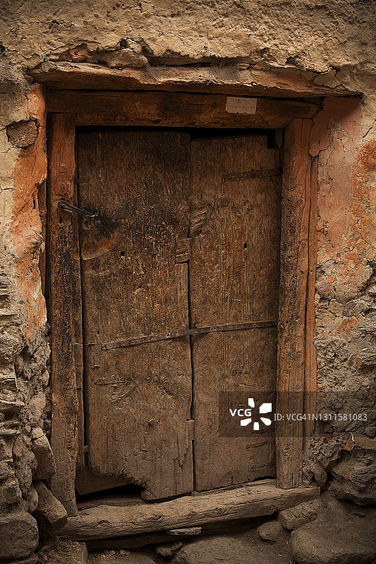 尼泊尔木斯塘地区藏族高原卡格贝尼村，泥土渲染石堆藏式村庄里一扇古老而质朴的木门图片素材