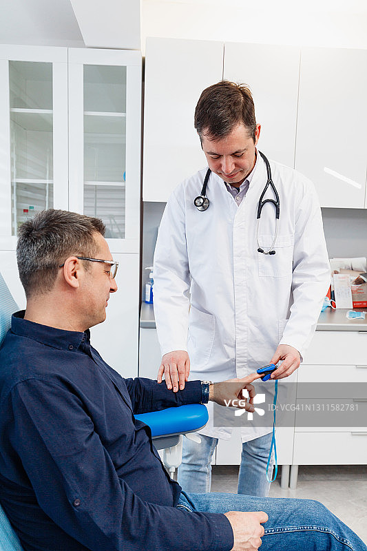 医生查看脉搏血氧仪测量病人手指血氧饱和度图片素材