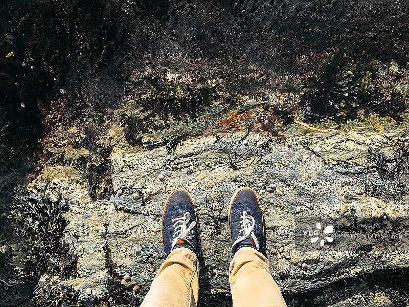 穿着蓝色鞋子和卡其色裤子站在岩石上的人图片素材