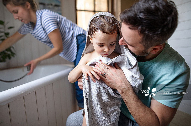 一家人和小女儿在家里浴室里，晚浴后擦干身体图片素材