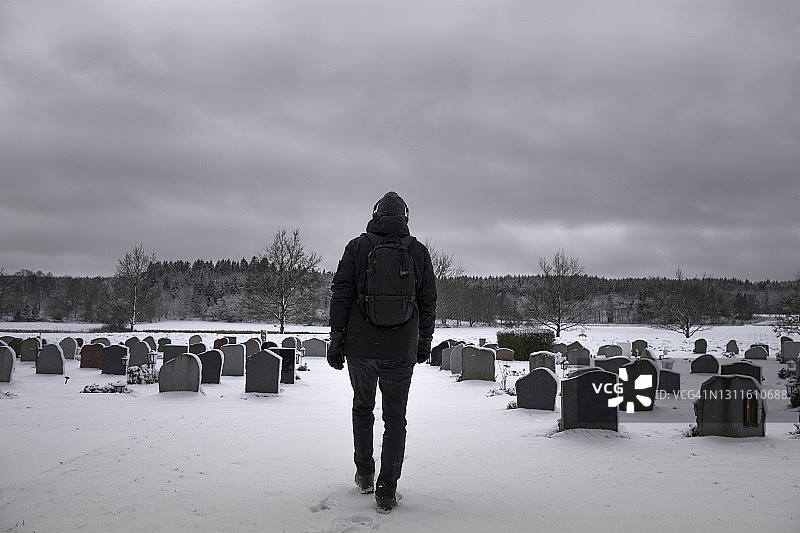 男人走过白雪覆盖的墓地图片素材
