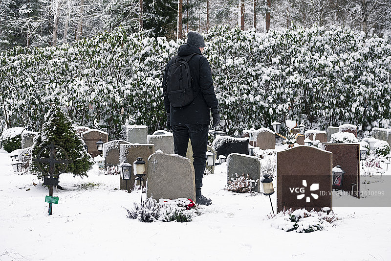 男子站在墓地的坟墓旁图片素材