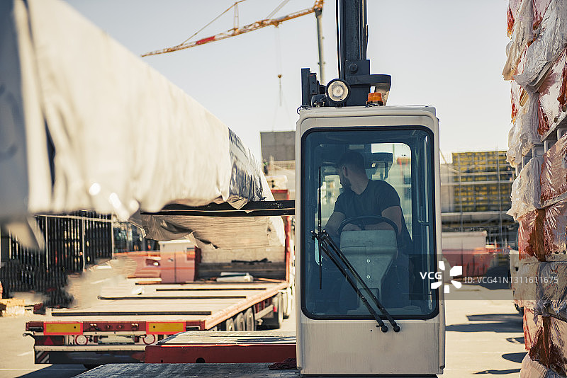 工人用叉车在卡车上装载建筑材料图片素材