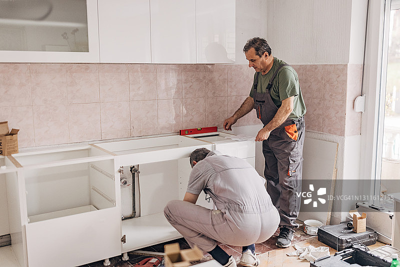 两位木匠正在安装新的白色厨房图片素材