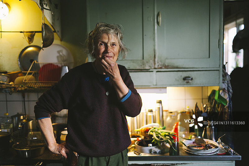 在厨房里看着镜头的微笑女人图片素材