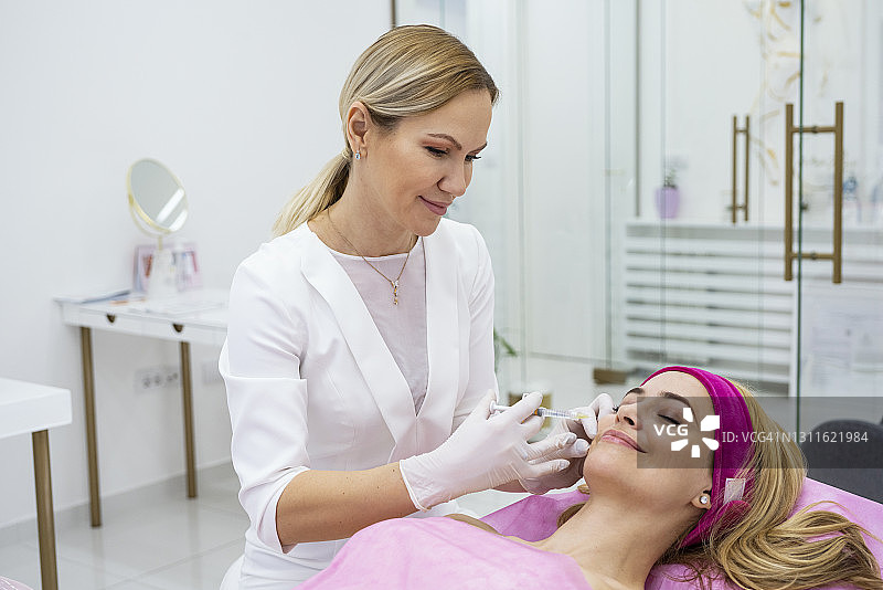 在美容医院接受医生或美容师服务的中年妇女图片素材