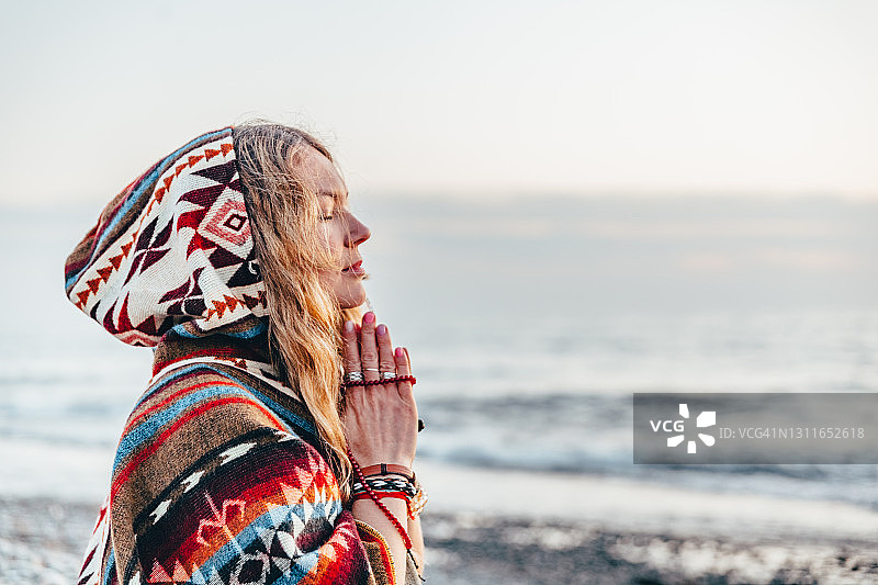 年轻长发女子在海滩上冥想/祈祷，宁静时刻，冥想，合十礼图片素材