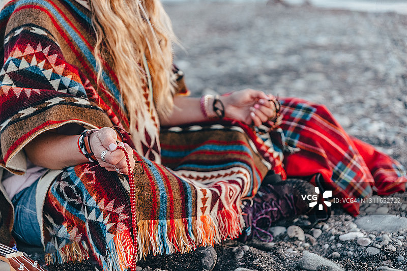 年轻长发女子在海滩上冥想/祈祷，点燃香。宁静的时刻。图片素材