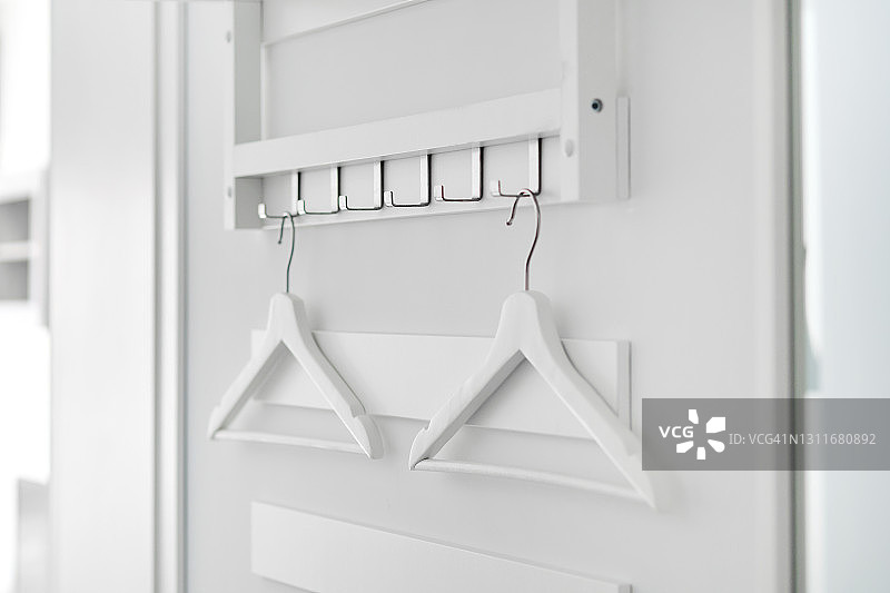 挂在室内挂钩上的两个白色木制衣架的特写图片素材