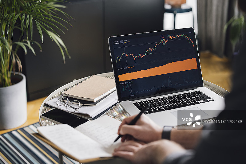 在家办公：男人在笔记本电脑屏幕上分析统计数据图片素材