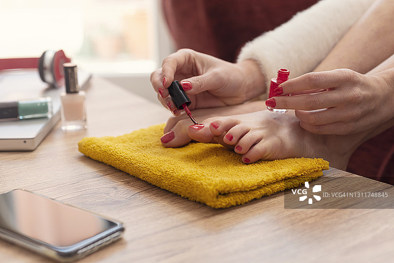 女人在脚趾上涂指甲油图片素材