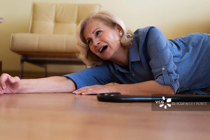 一位拄着拐杖的老年妇女在发生事故后躺在地板上图片素材