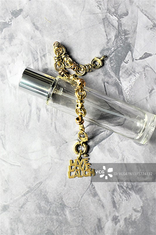 香水瓶与刻有“Live, Love, Laugh”字样的金色手镯图片素材