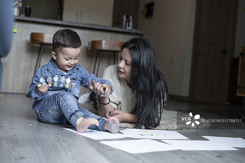 单身母亲和1到2岁的宝宝在客厅里玩耍、绘画的美好时光图片素材