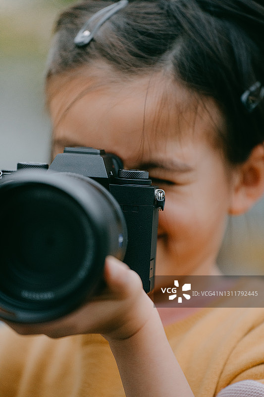 拿着相机并通过取景器观看的年轻女孩图片素材