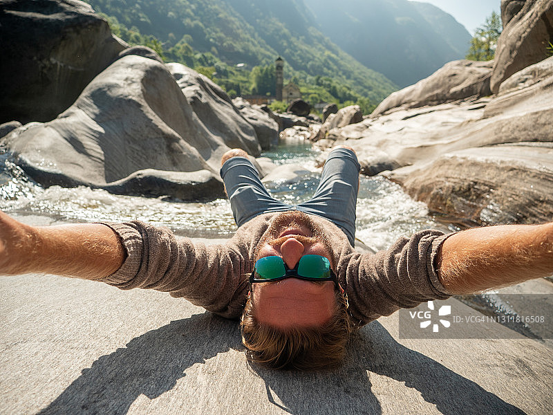 一名男子在春天于河边自拍，倒置视角图片素材
