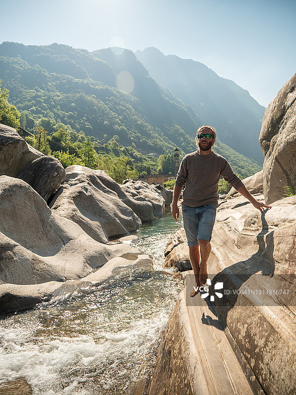 男人赤脚走在河边的岩石上图片素材