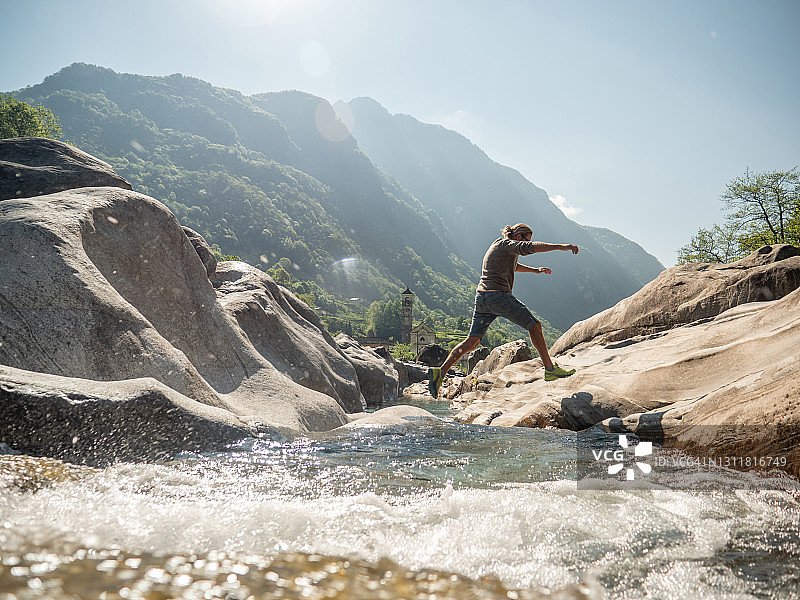 青年男子在河上跳跃图片素材