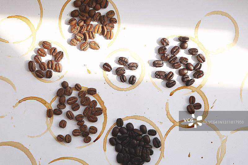 抽象咖啡滴和污渍背景下的烤咖啡豆图片素材