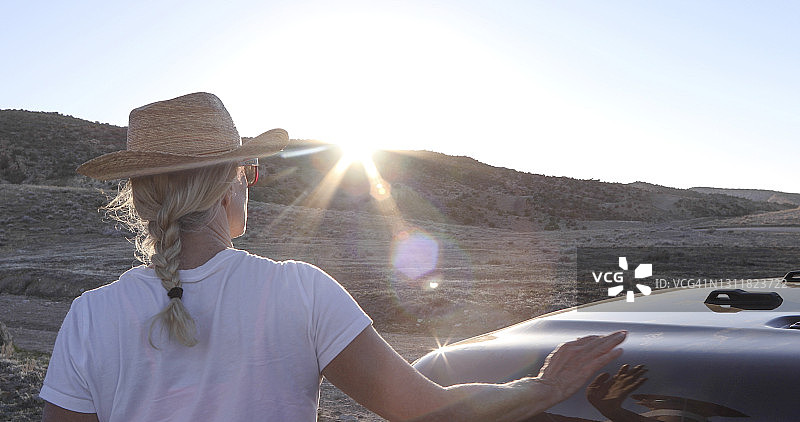 戴帽女子在车外看日出图片素材