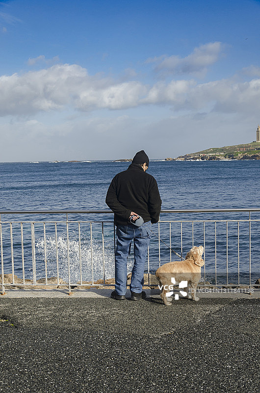 一位男人和他的狗在长廊上观海图片素材