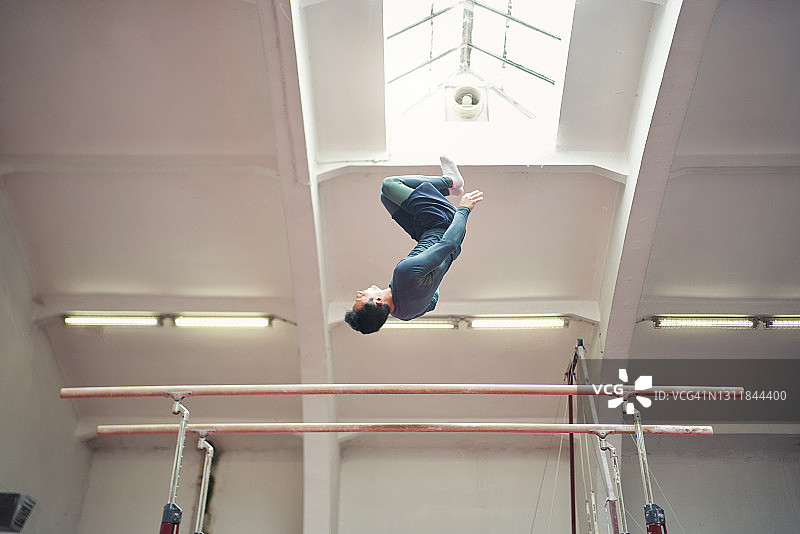 体操运动员在双杠上进行单人体操表演图片素材