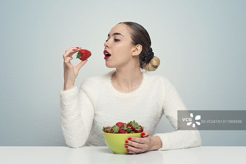 吃新鲜草莓的西班牙裔年轻女子图片素材