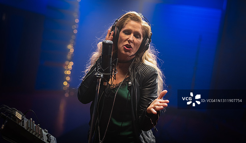 女歌手在录音室对着麦克风演唱图片素材
