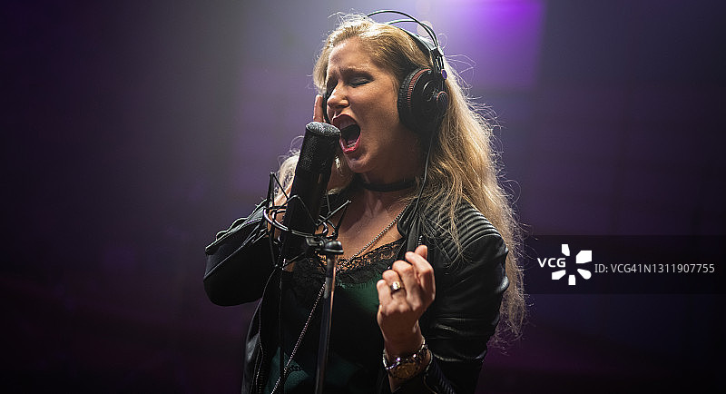 女歌手在录音室对着麦克风演唱图片素材