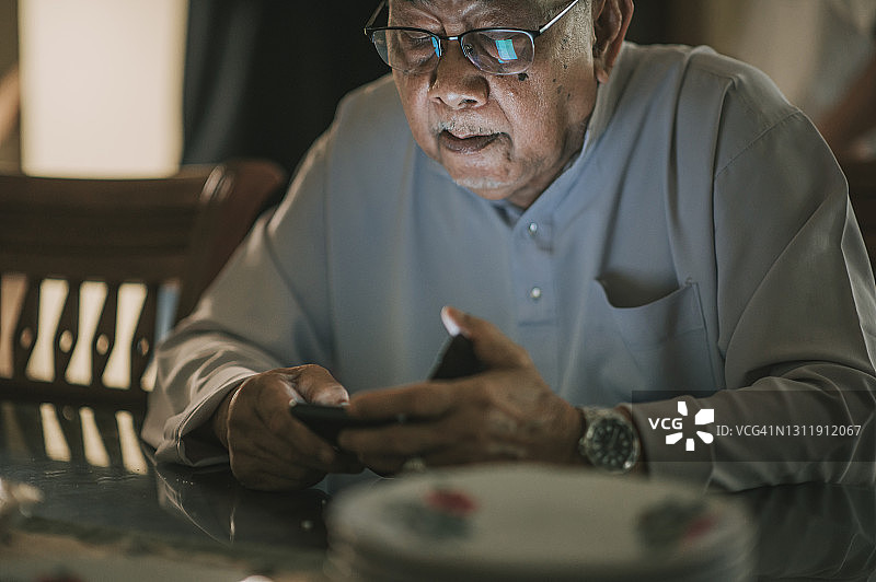 斋月开斋节马来西亚穆斯林曾祖父用智能手机等待团圆饭图片素材