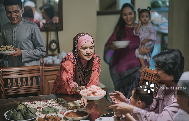 斋月开斋节马来奶奶、儿子和儿媳在餐厅为家人提供食物图片素材