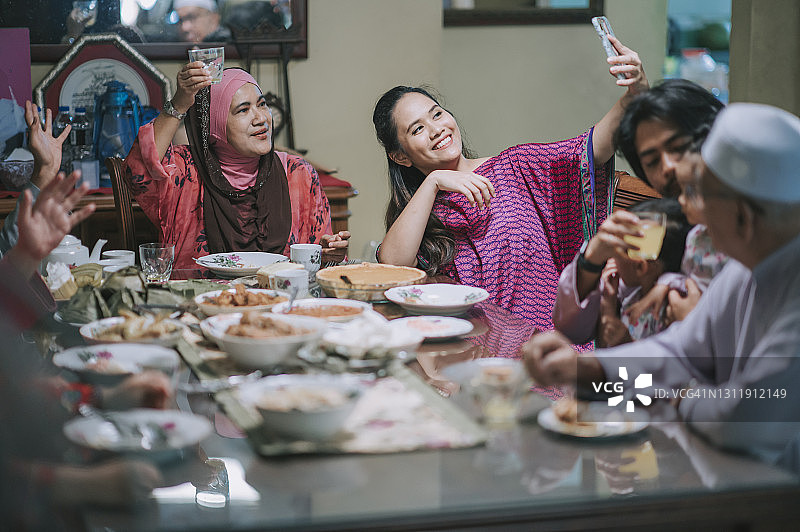 马来西亚穆斯林家庭在餐厅与亲戚视频通话，共进晚餐庆祝开斋节图片素材