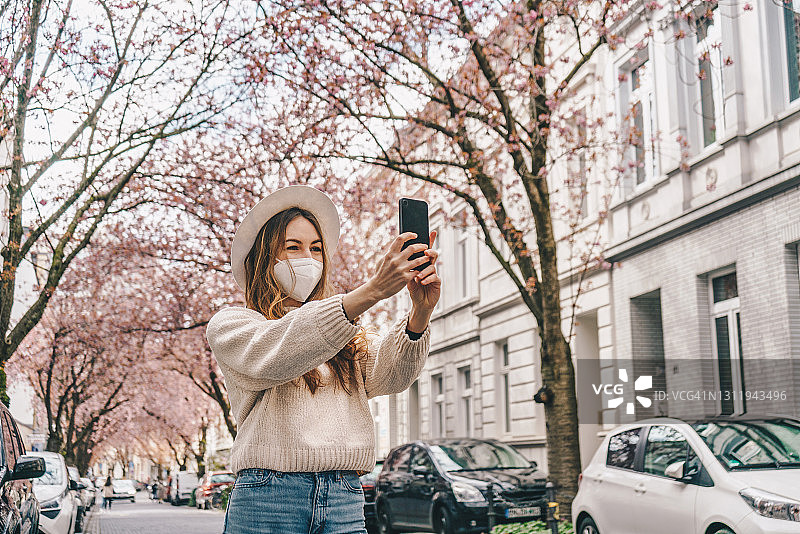 戴医用口罩在户外使用手机的女人图片素材