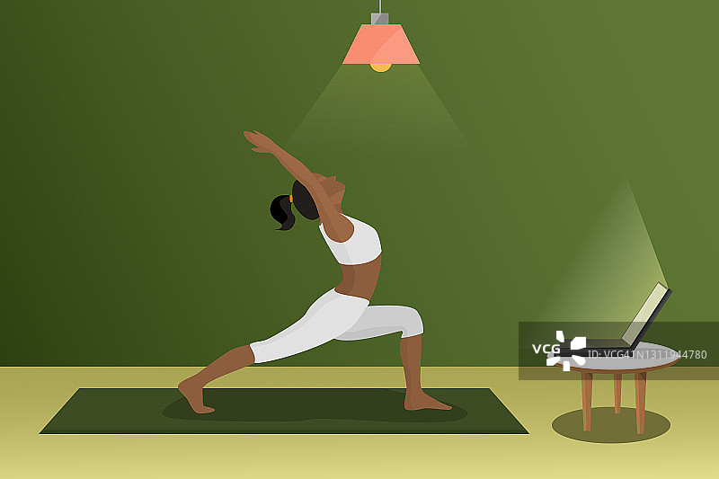 女人在房间里做瑜伽，在笔记本电脑前展示身体的柔韧性，用于在线瑜伽课堂图片素材