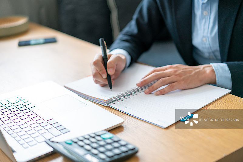 亚洲男性使用计算器和笔记本电脑图片素材