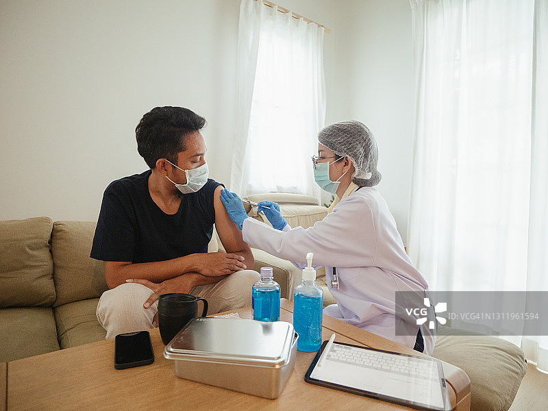 医生给中年男子注射新冠疫苗图片素材