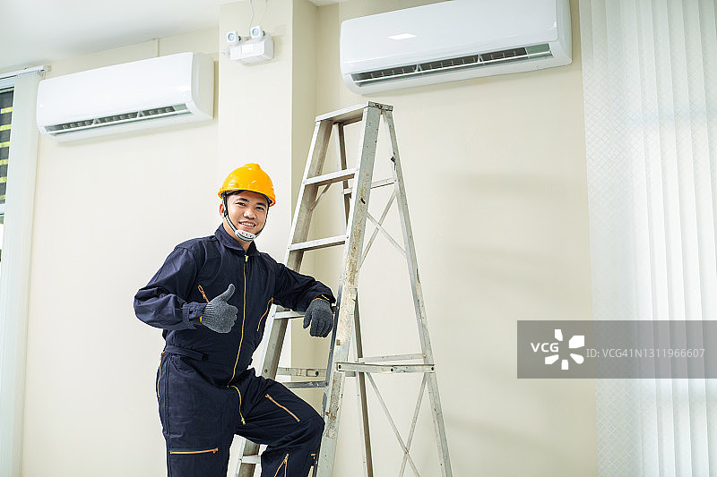 快乐的空调技术员正在室内维修空调图片素材
