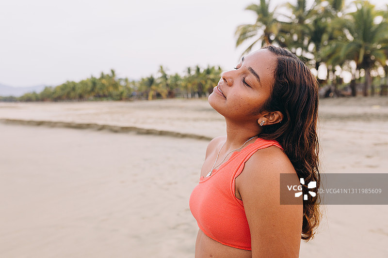 在沙滩上伸展身体的比基尼年轻女人图片素材