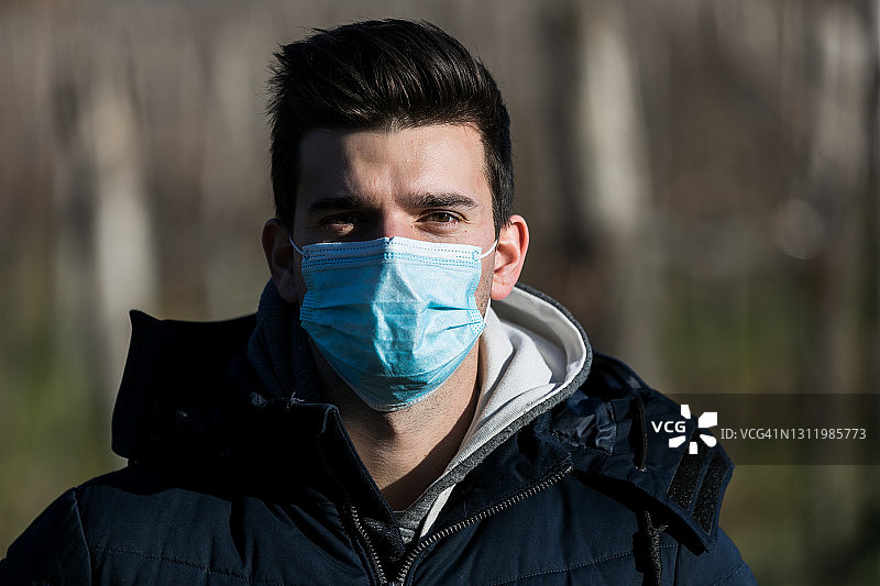 在户外大自然中戴防护口罩的年轻男人图片素材